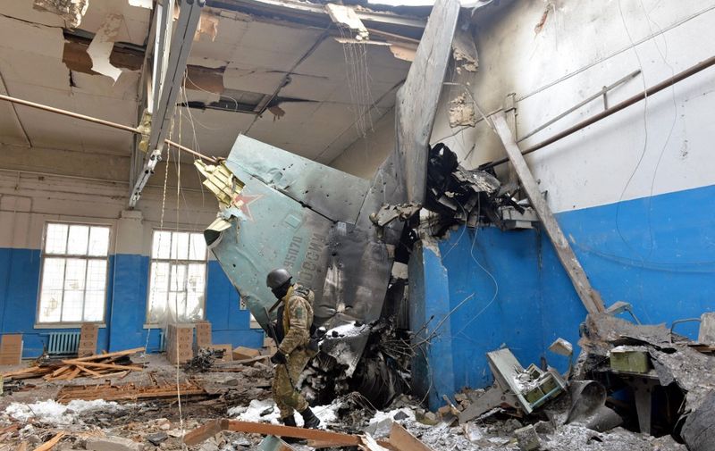 A member of the Ukrainian Territorial Defence Forces walks near remains of the Russian Sukhoi Su-25 assault aircraft crashed into the State Scientific Production Enterprise «Kommunar Corporation» in Ukraine's second-biggest city of Kharkiv on March 8, 2022. - On the 13th day of the war, the UN said the number of refugees flooding across Ukraine's borders had passed two million. (Photo by Sergey BOBOK / AFP)