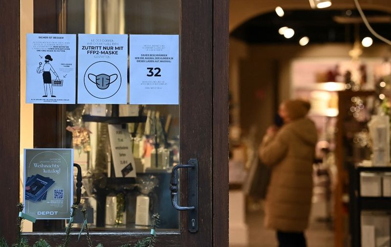 Information posters are seen at the entrance of a store in Muehldorf am Inn, southern Germany, on November 24, 2021, amid the ongoing coronavirus Covid-19 pandemic. (Photo by Christof STACHE / AFP)