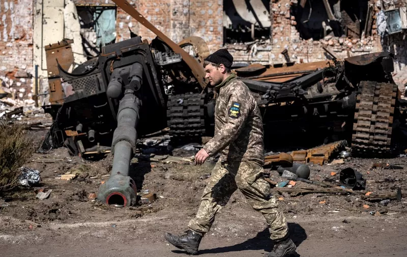 A Ukrainian serviceman walks between damaged Russian army tank and rubble of a destroyed building in the northeastern city of Trostyanets', on March 29, 2022. Ukraine said on March 26, 2022 its forces had recaptured the town of Trostyanets, near the Russian border, one of the first towns to fall under Moscow's control in its month-long invasion. (Photo by FADEL SENNA / AFP)