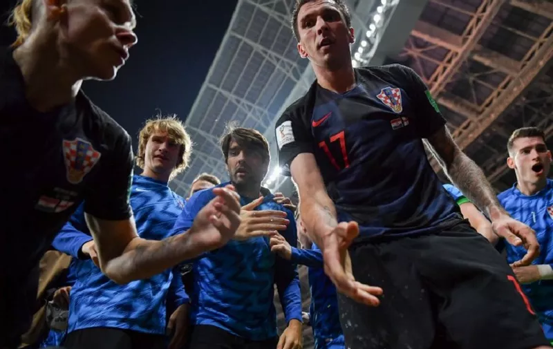 Croatia's forward Mario Mandzukic (C) offers to help AFP photographer Yuri Cortez after he fell on him with teammates while celebrating their second goal during the Russia 2018 World Cup semi-final football match between Croatia and England at the Luzhniki Stadium in Moscow on July 11, 2018. / AFP PHOTO / Yuri CORTEZ / RESTRICTED TO EDITORIAL USE - NO MOBILE PUSH ALERTS/DOWNLOADS