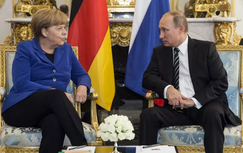 German Chancellor Angela Merkel (L) speaks with Russian President Vladimir Putin during a bilateral prior to a summit on Ukraine at the Elysee Palace in Paris, on October 2, 2015. Merkel, Ukrainian President Petro Porochenko, French President Francois Hollande and Russian President Vladimir Putin will take part in the summit. AFP PHOTO/ POOL /ETIENNE LAURENT / AFP / POOL / ETIENNE LAURENT