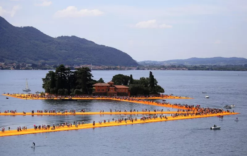 People walk on the monumental installation entitled 'The Floating Piers' created by artist Christo Vladimirov Javacheff on Iseo Lake, in northern Italy, on June 18, 2016.
Some 200,000 floating cubes create a 3-kilometers runway connecting the village of Sulzano to the small island of Monte Isola on the Iseo Lake for a 16-day outdoor installation opening today. / AFP PHOTO / MARCO BERTORELLO / RESTRICTED TO EDITORIAL USE - MANDATORY MENTION OF THE ARTIST UPON PUBLICATION - TO ILLUSTRATE THE EVENT AS SPECIFIED IN THE CAPTION