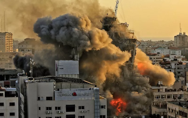 Heavy smoke and fire rise from Al-Sharouk tower as it collapses after being hit by an Israeli air strike, in Gaza City on May 12, 2021. - An Israeli air strike destroyed a multi-storey building in Gaza City today, AFP reporters said, as the Jewish state continued its heavy bombardment of the Palestinian enclave. (Photo by QUSAY DAWUD / AFP)