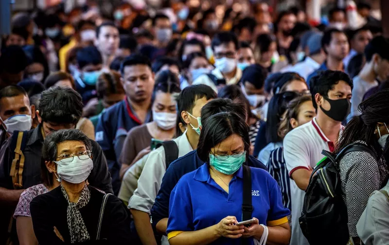 Commuters, wearing facemasks amid fears of the spread of the COVID-19 novel coronavirus, wait for a canal boat in Bangkok on March 2, 2020. - A Thai man has died from complications doctors say were due to the deadly coronavirus, though health officials were reluctant on March 2 to conclusively confirm the cause of his death. (Photo by Mladen ANTONOV / AFP)