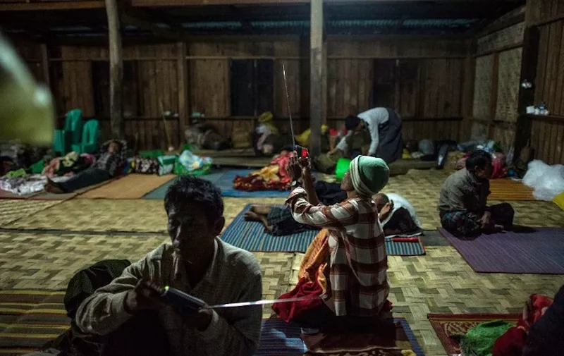 This picture taken on May 11, 2018 shows two Internally displaced men listening to the radio in a temporary shelter in Danai, Kachin state. 
Thousands of people have fled renewed fighting between Myanmar's army and ethnic insurgents in the country's remote north, a United Nations official said, as a long-simmering conflict intensifies. / AFP PHOTO / Ye Aung Thu