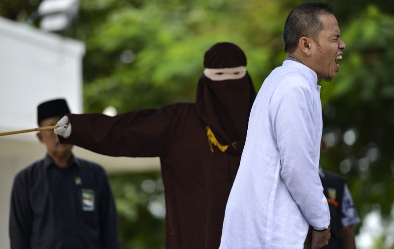 Aceh Ulema Council (MPU) member Mukhlis reacts as he is whipped in public by a member of the Sharia police in Banda Aceh on October 31, 2019. - An Indonesian man working for an organisation which helped draft strict religious laws ordering adulterers to be flogged was himself publically whipped on October 31 after he was caught having an affair with a married woman. (Photo by CHAIDEER MAHYUDDIN / AFP)