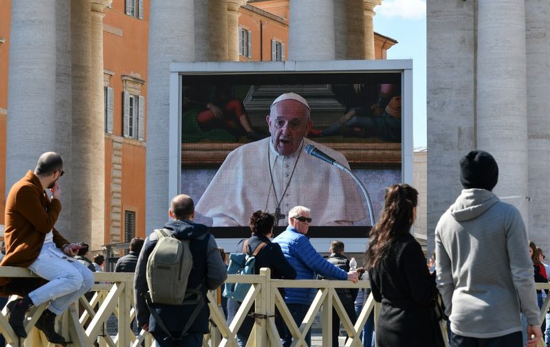 People watch a screen live-broadcasting Pope Francis' Sunday Angelus prayer on St. Peter's Square at the Vatican on March 8, 2020, after millions of people were placed under forced quarantine in northern Italy as the government approved drastic measures in an attempt to halt the spread of the COVID-19 outbreak, caused by the novel coronavirus that is sweeping the globe. - On top of the forced quarantine of 15 million people in vast areas of northern Italy until April 3, the government has also closed schools, nightclubs and casinos throughout the country, according to the text of the decree published on the government website. With more than 230 fatalities, Italy has recorded the most deaths from the COVID-19 disease of any country outside China, where the outbreak began in December. (Photo by Alberto PIZZOLI / AFP)