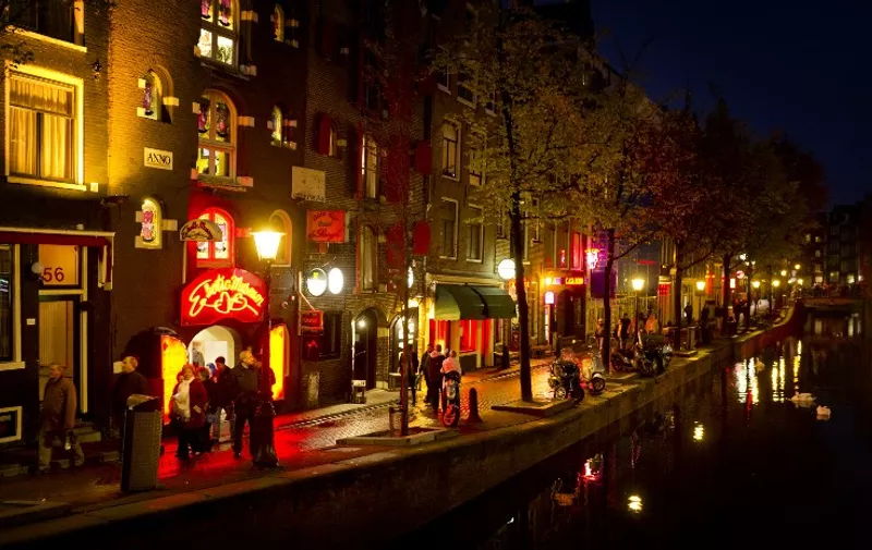 People walk through the red-light district, known as De Wallen, in Amsterdam, on October 13, 2011. De Wallen is the largest red-light district situated in the centre of Amsterdam and a major tourist attraction. The local city government of Amsterdam has initiated a project to buy real estate in the neighborhood to diversify businesses and decrease crime. AFP PHOTO / ANP / KOEN VAN WEEL   ***Netherlands out - Belgium out*** / AFP PHOTO / ANP / Koen van Weel