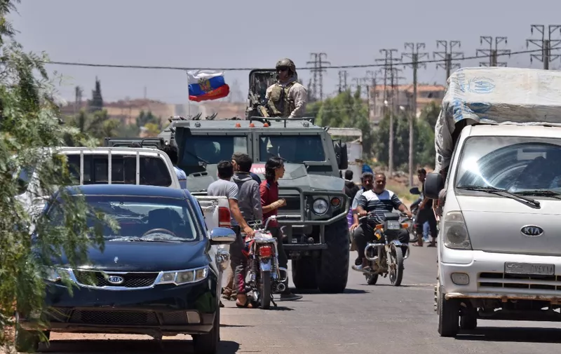 Russians forces are seen as displaced Syrians from the Daraa province come back to their hometown in Bosra, southwestern Syria, on July 11, 2018. - The regime assault against Syria's southern province of Daraa has pushed more than 320,000 people to flee their homes, while the government has been able to retake several areas. (Photo by Mohamad YUSUF / AFP)