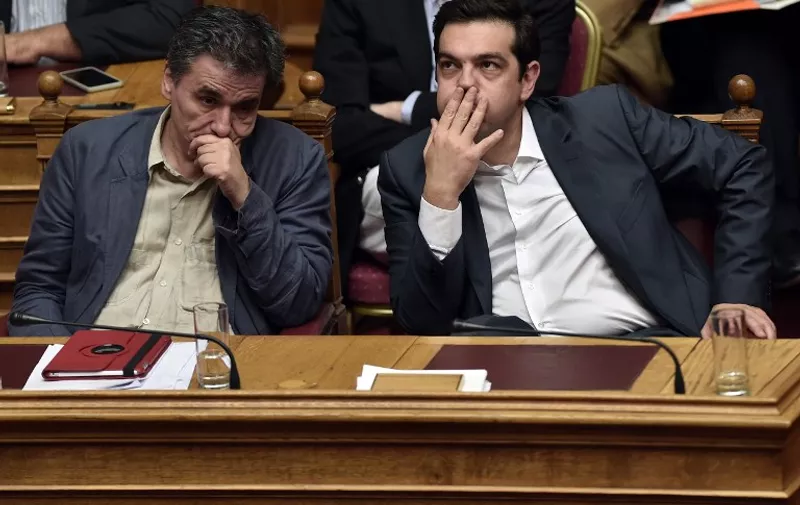 TOPSHOTS
Greek Prime Minister Alexis Tsipras (R) and Finance Minister Eyclid Tsakalotos react during a parliament session in Athens on July 15, 2015. AFP PHOTO / ARIS MESSINIS