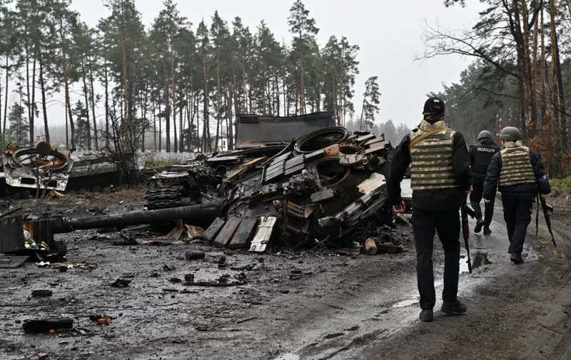 Ukrainian policemen walk by the wreckage of Russian tanks and armoured personnel carriers (APC) in Dmytrivka village, west of Kyiv, on April 2, 2022 as Ukraine says Russian forces are making a "rapid retreat" from northern areas around Kyiv and the city of Chernigiv. (Photo by Genya SAVILOV / AFP)