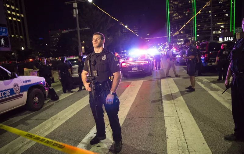 Police officers stand guard at a baracade following the sniper shooting in Dallas on July 7, 2016. 
A fourth police officer was killed and two suspected snipers were in custody after a protest late Thursday against police brutality in Dallas, authorities said. One suspect had turned himself in and another who was in a shootout with SWAT officers was also in custody, the Dallas Police Department tweeted.
 / AFP PHOTO / Laura Buckman