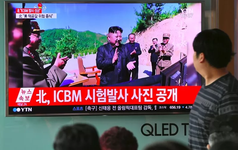 People watch a television news broadcast showing a picture of North Korean leader Kim Jong-Un (C) celebrating his country's test launch of an intercontinental ballistic missile (ICBM), at a railway station in Seoul on July 4, 2017.
North Korea proclaimed on July 4 that it had successfully tested an intercontinental ballistic missile -- a watershed moment in its push to develop a nuclear weapon capable of hitting the United States. / AFP PHOTO / JUNG Yeon-Je