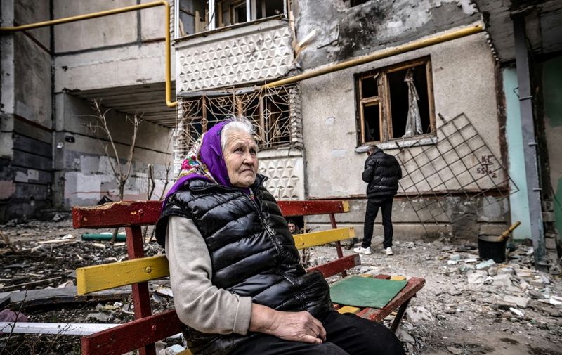 A woman looks on as she sits on a bench outside a destroyed building in the eastern Ukraine city of Kharkiv on april 2, 2022, as Ukraine said today Russian forces were making a "rapid retreat" from northern areas around the capital Kyiv and the city of Chernigiv. (Photo by FADEL SENNA / AFP)