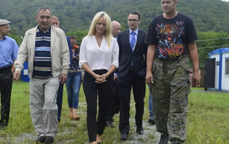 US-Canadian actress and animal rights activist Pamela Anderson (C) is pictured during her visit to to a rehabilitation centre for the animals affected by flood in Ussuriysk, in the village of Alekseevka, outside Vladivostok on September 3, 2015. Anderson urged Russia to join her fight to save whales as she met the country's environment minister in the far eastern city of Vladivostok. The 48-year-old actress met Environment Minister Sergei Donskoi as Vladivostok hosts an international economic forum. AFP PHOTO / POOL / TASS / YURI SMITYUK / EASTERN ECONOMIC FORUM