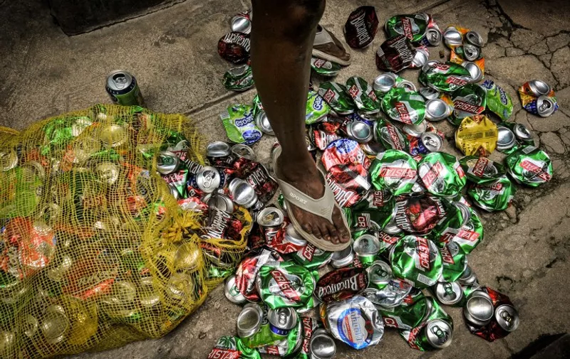 TO GO WITH AFP STORY BY CARLOS BATISTA
A Cuban crushes cans of beer and soft drinks to sell them as raw material, on June 28, 2013 in Havana. The government of President Raul Castro decided to promote the recycling of raw materials.  AFP PHOTO/STR / AFP PHOTO / STR