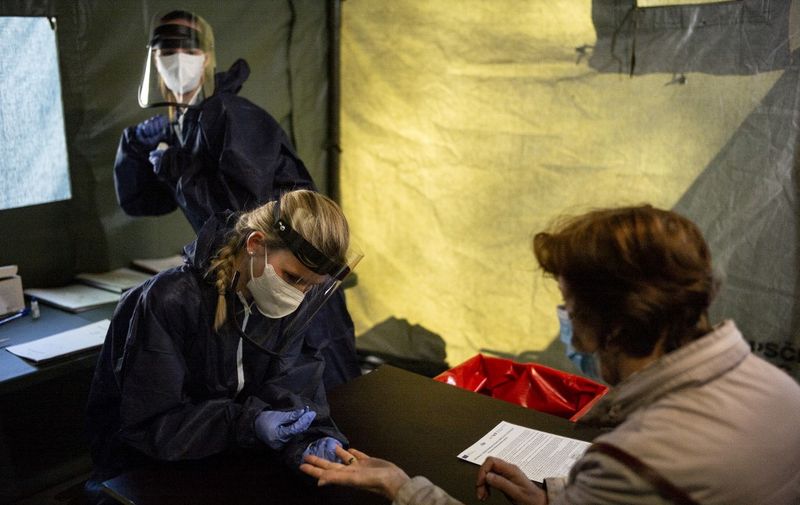 A woman is being tested for the novel coronavirus inside a medical tent at a park on April 23, 2020 in Prague, as a research is conducted to evaluate undetected infections with the coronavirus in the population. - The Czech government on April 20, 2020 introduced a five-stage plan to ease lockdown measures to combat the spread of the novel coronavirus, starting on April 20 and ending June 8. (Photo by Michal Cizek / AFP)
