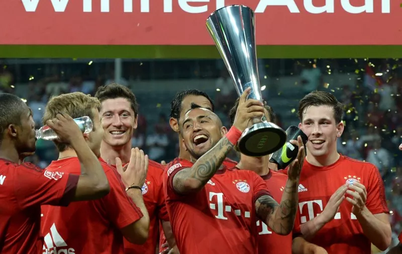 Bayern Munich's Chilean midfielder Arturo Vidal and his team-mates celebrate with the trophy after the Audi Cup final football match Real Madrid vs FC Bayern Munich in Munich, southern Germany, on August 5, 2015. Bayern Munich won the match 1-0. AFP PHOTO / CHRISTOF STACHE