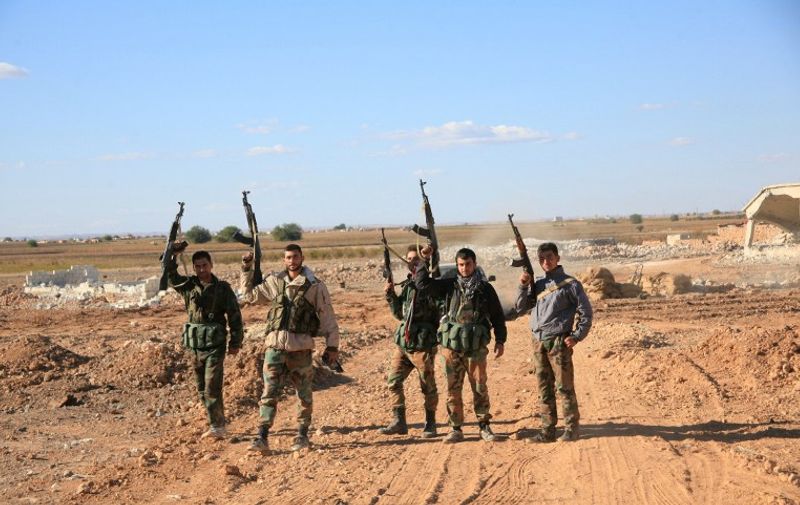 A group of Syrian pro-government forces raise their guns in celebration on the outskirts of Kweyris near the Kweyris military air base, east of the Syrian province of Aleppo on November 10, 2015. Syrian regime troops broke a more than a year-long siege by IS fighters at the major military air base and reached government forces inside the base.  AFP PHOTO / GEORGE OURFALIAN
