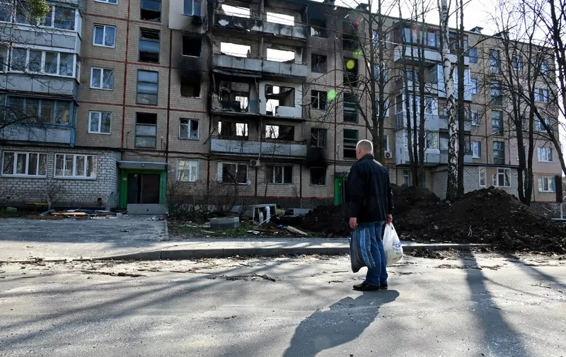 A man looks at five storey residential buildings in the second large Ukrainian city of Kharkiv, on April 10, 2022. (Photo by SERGEY BOBOK / AFP)