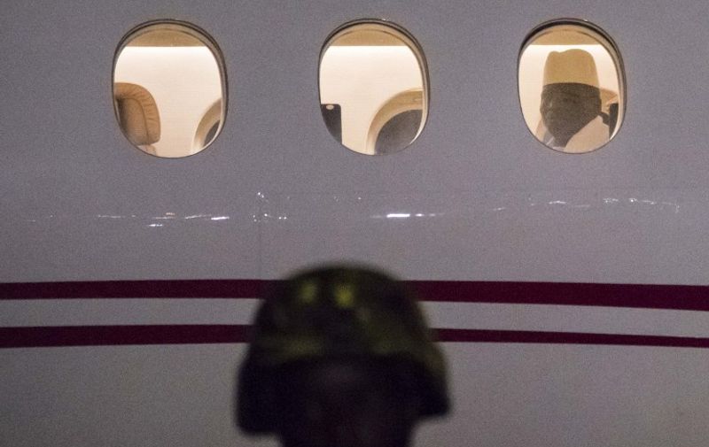 Former president Yaya Jammeh the Gambia's leader for 22 years, looks through the window from the plane as he leaves the country on 21 January 2017 in Banjul airport.
Yahya Jammeh, the Gambia's leader for 22 years, flew out of the country on January 21, 2017 after declaring he would step down and hand power to President Adama Barrow, ending a political crisis. An AFP journalist at the airport saw Jammeh board an unmarked plane heading for an unspecified destination, seen off by a delegation of dignitaries and soldiers. / AFP PHOTO / STRINGER