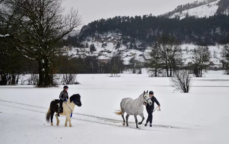 Girls take their horses for a walk following snow falls in Planina, on January 23, 2023. (Photo by Jure Makovec / AFP)