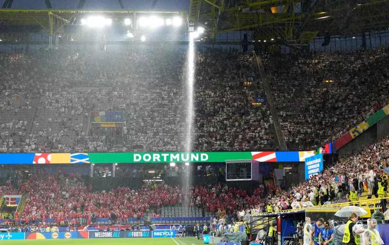 Rain water pours from the roof of the stadium as the match is suspended due to adverse weather during the round of sixteen match between Germany and Denmark at the Euro 2024 soccer tournament in Dortmund, Germany, Saturday, June 29, 2024. (AP Photo/Martin Meissner)