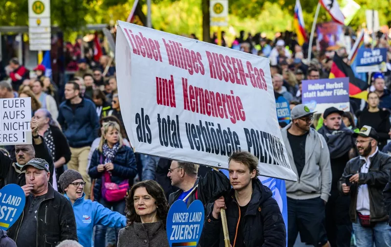 A protester holds up a sign reading: "I'd rather have cheap Russian gas and nuclear energy than completely stupid politicians" during a rally of far-right groups including the Alternative for Germany (AfD) party against rising prices in Berlin on October 8, 2022. (Photo by John MACDOUGALL / AFP)