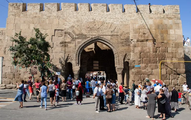 (FILES) A file picture taken on September 19, 2015 shows people walking in front of the Naryn-Kala Fortress in Derbent. 
One person was killed and 11 were injured in a shooting at a UNESCO heritage site in Russia's volatile North Caucasus region of Dagestan, local health authorities said on December 30, 2015. The incident occurred on December 29 night near the fortress at Derbent, which claims to be Russia's oldest city. / AFP / ILYAS HAJJI