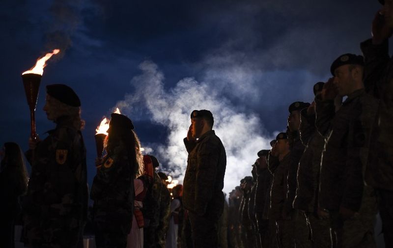 Kosovo Albanians dressed in military costumes carry torches and salute during a bonfire ceremony, marking the 19th anniversary of the killing of Kosovo Liberation Army (KLA) founding member and commander Adem Jashari, on March 7, 2017 in Prekaz. 
Jashari was among 45 members of family killed by Serb security forces in the village of Prekaz ,west of Kosovo capital Pristina, sparking a full-blown rebel insurgency.  / AFP PHOTO / Armend NIMANI