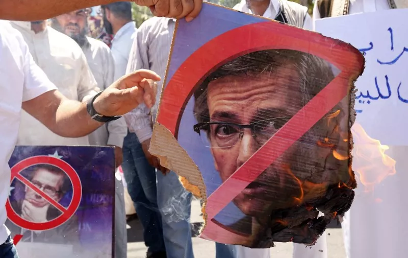 Libyan protesters set a portrait of United Nations envoy Bernardino Leon on fire during a demonstration outside the General National Congress (GNC) in Tripoli on July 1, 2015, against the UN-led negotiations to resolve the country's ongoing crisis. Libya's rival parliaments have been locked in talks in Morocco, and on June 29, 2015, Leon said he hoped they would endorse his proposals for a unity government this week after they failed to do so at the weekend. AFP PHOTO / MAHMUD TURKIA