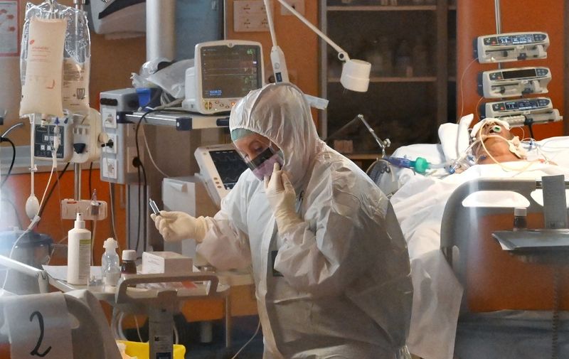 A medical worker wearing a protective gear works by a patient (Rear R) on March 24, 2020 at the new COVID 3 level intensive care unit for coronavirus COVID-19 cases at the Casal Palocco hospital near Rome, during the country's lockdown aimed at stopping the spread of the COVID-19 (new coronavirus) pandemic. (Photo by Alberto PIZZOLI / AFP)