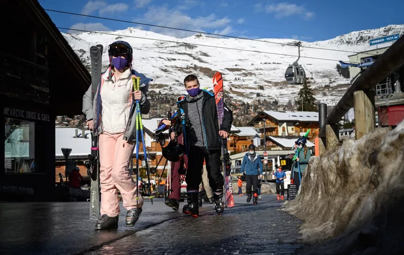Skiers walk in the Alpine resort of Verbier, well known by British ski holiday makers, on December 22, 2020. - Switzerland on December 21, imposed an entry ban on arrivals from Britain and South Africa and ordered retroactive quarantine for all arrivals from the countries since December 14. The federal government said the move was intended to stop tourism from countries following the discovery there of new, more contagious variants of Covid-19. (Photo by Fabrice COFFRINI / AFP)