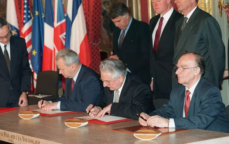 (1st Row L to R) Serbian president Slobodan Milosevic, Bosnian President Alija Izetbegovic (C) and Croatian President Franjo Tudjman sign the Dayton peace accord on Bosnia, as (2d row L to R) Spanish Prime Minister Felipe Gonzalez, US President Bill Clinton and French President Jacques Chirac look on, 14 December 1995 at the Elysee Palace in Paris. (Photo by MICHEL GANGNE / AFP)