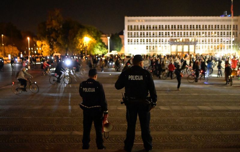 Police officers stand as people ride their bikes during an anti-government protest in Ljubljana, Slovenia, on October 9, 2020. (Photo by Jure Makovec / AFP)