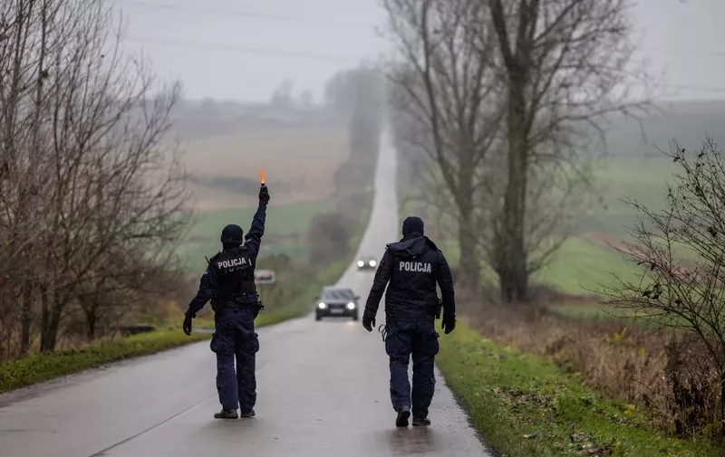 Police officers stop cars on November 17, 2022 at the entrance to eastern Poland village of Przewodow where a missile strike killed two men two days ago, near the border with war-ravaged Ukraine. Two men aged about 60 were killed when a missile hit the southeastern Polish village of Przewodow, some six kilometres (four miles) from the Ukrainian border, on Tuesday afternoon. (Photo by Wojtek RADWANSKI / AFP)