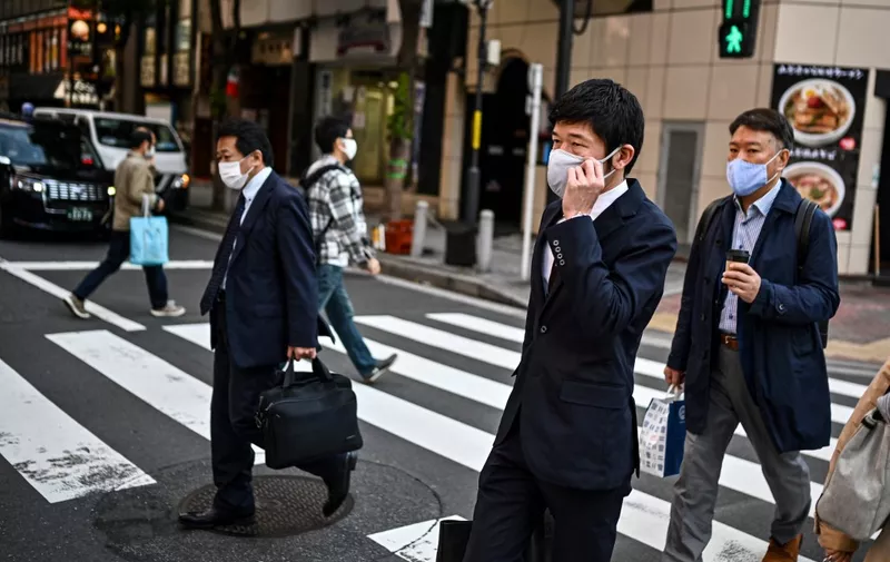 People walk on a pedestrian crossing in Tokyo on November 16, 2020, as government data showed Japan's economy exited recession in the third quarter, growing a better-than-expected 5.0 percent following a record contraction. (Photo by Charly TRIBALLEAU / AFP)