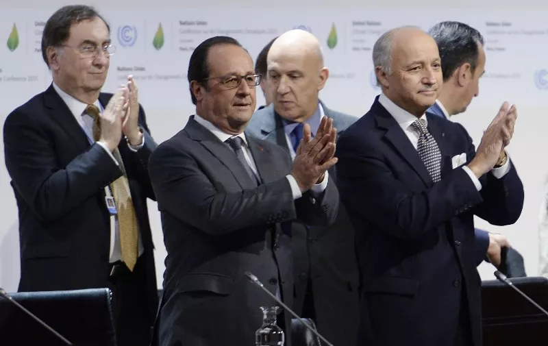 French President Francois Hollande (C) and French Foreign Minister Laurent Fabius (R) applaud after a statement at the COP21 Climate Conference in Le Bourget, north of Paris, on December 12, 2015. The years-long quest for a universal pact to avert catastrophic climate change neared the finish line today with conference host France announcing that the final draft had been completed in the early hours of the morning. AFP PHOTO / MIGUEL MEDINA / AFP / MIGUEL MEDINA