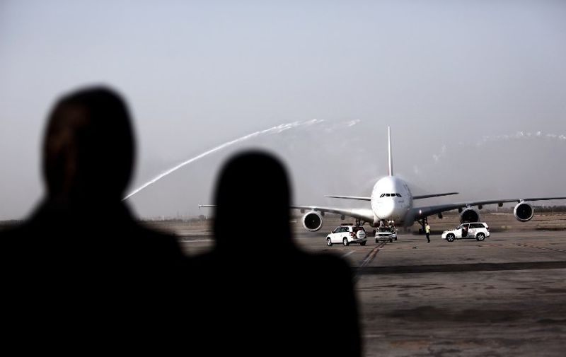 Iranian women watch an Airbus A380-800 airctaft of Emirates Airline being given a water cannon salute after landing at Tehran's IKA airport on September 30, 2014. Dubai's Emirates Airline made a one-off flight to the Iranian capital for the first time with its flagship Airbus A380 plane to celebrate its recent introduction of more flights on the route. AFP PHOTO/BEHROUZ MEHRI / AFP PHOTO / BEHROUZ MEHRI