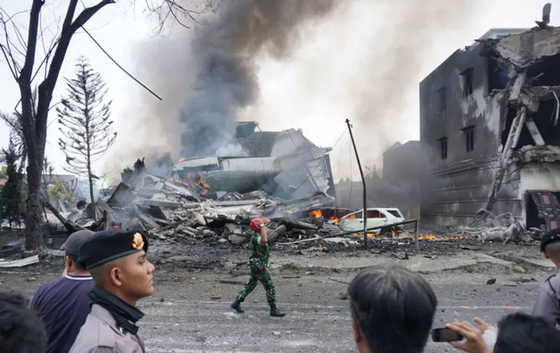 Indonesian police and military officials secure the crash site of military Hercules plane in Medan, North Sumatra province on June 30, 2015.  An Indonesian military transport plane crashed shortly after take off in the city, an official said, with the plane exploding in a ball of flames.    AFP PHOTO / Muhammad ZULFAN DALIMUNTHE