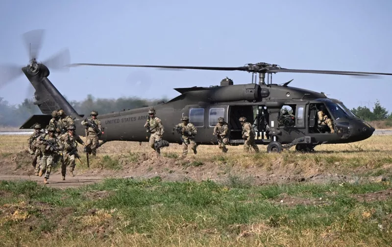 Military personnel of the US Army's 101st Airborne Division leave a helicopter during a demonstration drill at Mihail Kogalniceanu Airbase near Constanta, Romania on July 30, 2022. - Members of the 101st Airborne Division (Air Assault) headquarters and its 2nd Brigade Combat Team in a ceremony marked their official arrival in Europe at the airbase. The ceremony was followed by a 'Romania/US Air and Land Showcase', a combined US Army and Romanian Army capabilities demonstration. (Photo by Daniel MIHAILESCU / AFP)