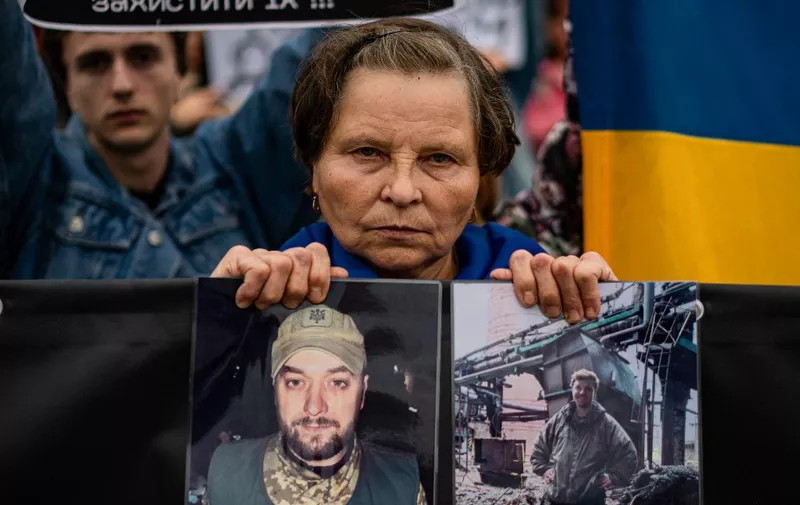 A woman holds pictures of her son during a demonstration demanding to speed up the release from Russia authority of the Ukrainian prisoners involved in the battle of the Azovstal steel plant in Mariupol, downtown Kiev, on October 1, 2022, amid the Russian military invasion of Ukraine. (Photo by Dimitar DILKOFF / AFP)