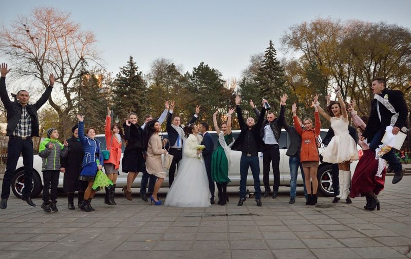 People pose near a limousine as they take part in a wedding near the Cathedral Park in Chisinau on November 11, 2016. (Photo by DANIEL MIHAILESCU / AFP)