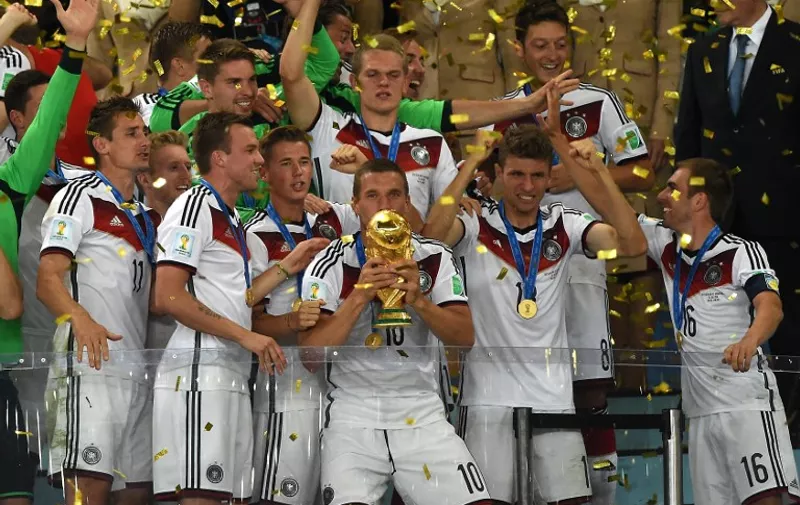 Germany's forward Lukas Podolski (front-C) holds up the World Cup trophy as he celebrates with his teammates after winning the 2014 FIFA World Cup final football match between Germany and Argentina 1-0 following extra-time at the Maracana Stadium in Rio de Janeiro, Brazil, on July 13, 2014.    AFP PHOTO / PEDRO UGARTE / AFP / PEDRO UGARTE