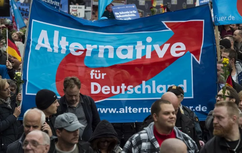 Supporters of the right-wing populist Alternative for Germany (AfD) party display an AfD banner during a demonstration by AfD supporters in Berlin on November 7, 2015. Thousands of protesters marched through the streets of the capital asking for the ouster of German Chancellor Angela Merkel and a curb on the number of asylum-seekers entering Germany. AFP PHOTO / JOHN MACDOUGALL