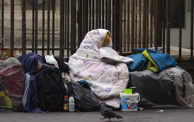 A homeless woman is wrapped in a blanket on the sidewalk of a Parisian street, on December 3, 2014. AFP PHOTO JOEL SAGET / AFP PHOTO / JOEL SAGET