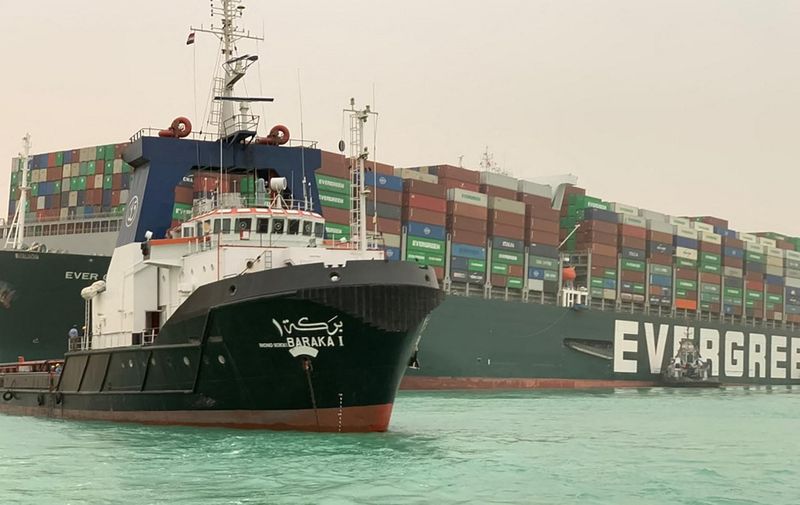 A handout picture released by the Suez Canal Authority on March 24, 2021 shows the Panama-flagged MV Ever Given (operated by Taiwan-based Evergreen Marine), a 400-metre- (1,300-foot-)long and 59-metre wide vessel, lodged sideways and impeding all traffic across the waterway of Egypt's Suez Canal. - A giant container ship ran aground in the Suez Canal after a gust of wind blew it off course, the vessel's operator said on March 24, 2021, bringing marine traffic to a halt along one of the world's busiest trade routes. (Photo by - / Suez CANAL / AFP) / The erroneous mention[s] appearing in the metadata of this photo by Marina PASSOS has been modified in AFP systems in the following manner: [STR] instead of [Marina Passos]. Please immediately remove the erroneous mention[s] from all your online services and delete it (them) from your servers. If you have been authorized by AFP to distribute it (them) to third parties, please ensure that the same actions are carried out by them. Failure to promptly comply with these instructions will entail liability on your part for any continued or post notification usage. Therefore we thank you very much for all your attention and prompt action. We are sorry for the inconvenience this notification may cause and remain at your disposal for any further information you may require.