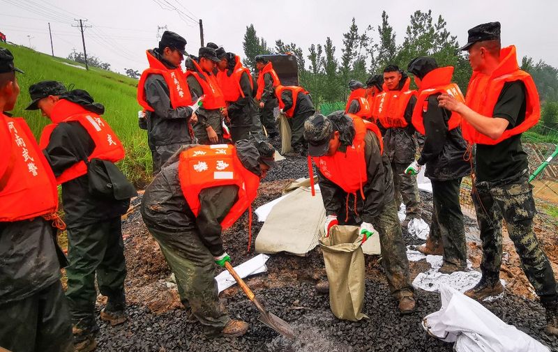 China's paramilitary police officers reinforce a lake dyke following heavy rains which caused severe flooding near Zhengzhou city, in China's central Henan province on July 22, 2021. (Photo by AFP) / China OUT