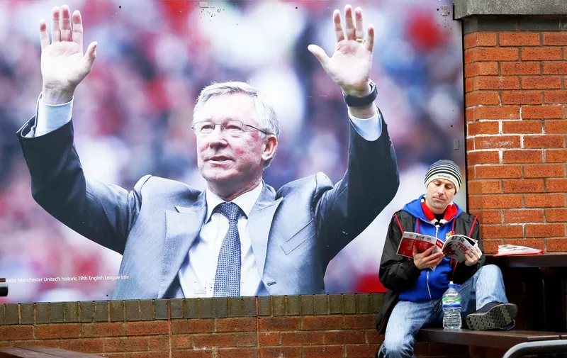 A fan reads a programme next to an image of former manager Sir Alex Ferguson before the UEFA Europa League Round of Sixteen, Second Leg match at Old Trafford, Manchester., Image: 325545050, License: Rights-managed, Restrictions: , Model Release: no, Credit line: Profimedia, Press Association