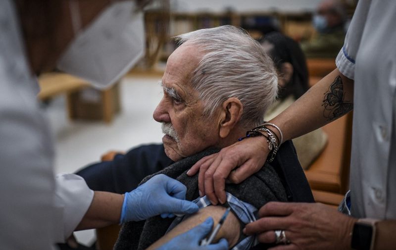 An elderly man receives a dose of Covid-19 vaccine, at a nursing home in Carcavelos, on November 30, 2021. - Portugal, the country with the highest vaccination coverage rate in Europe, had to restore control measures for the Covid-19 pandemic, while relying on a new vaccination campaign. (Photo by PATRICIA DE MELO MOREIRA / AFP)
